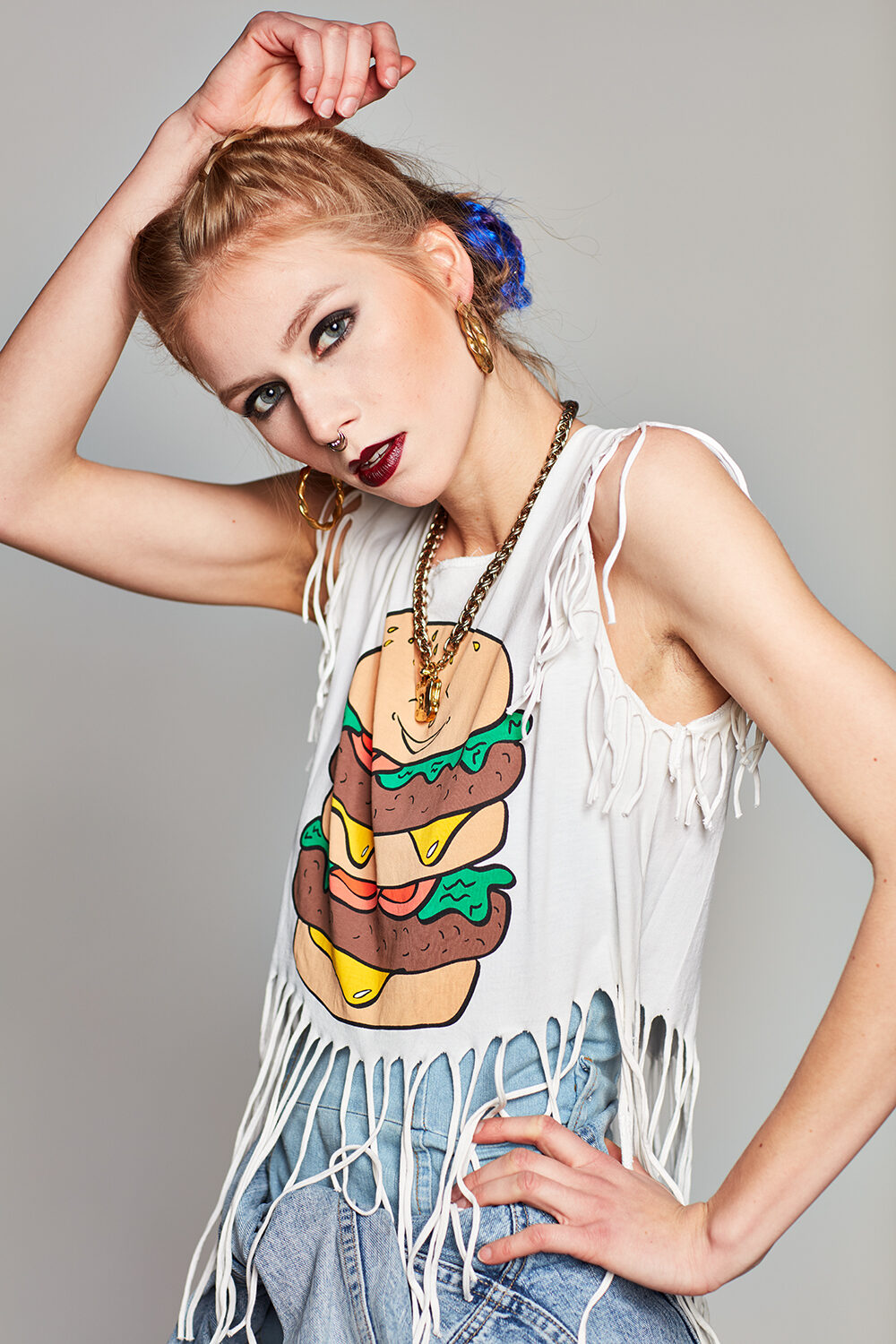 Denim-Editorial: Model Maria im weißen Fransen-Top mit Burger-Print über Jeansshorts.