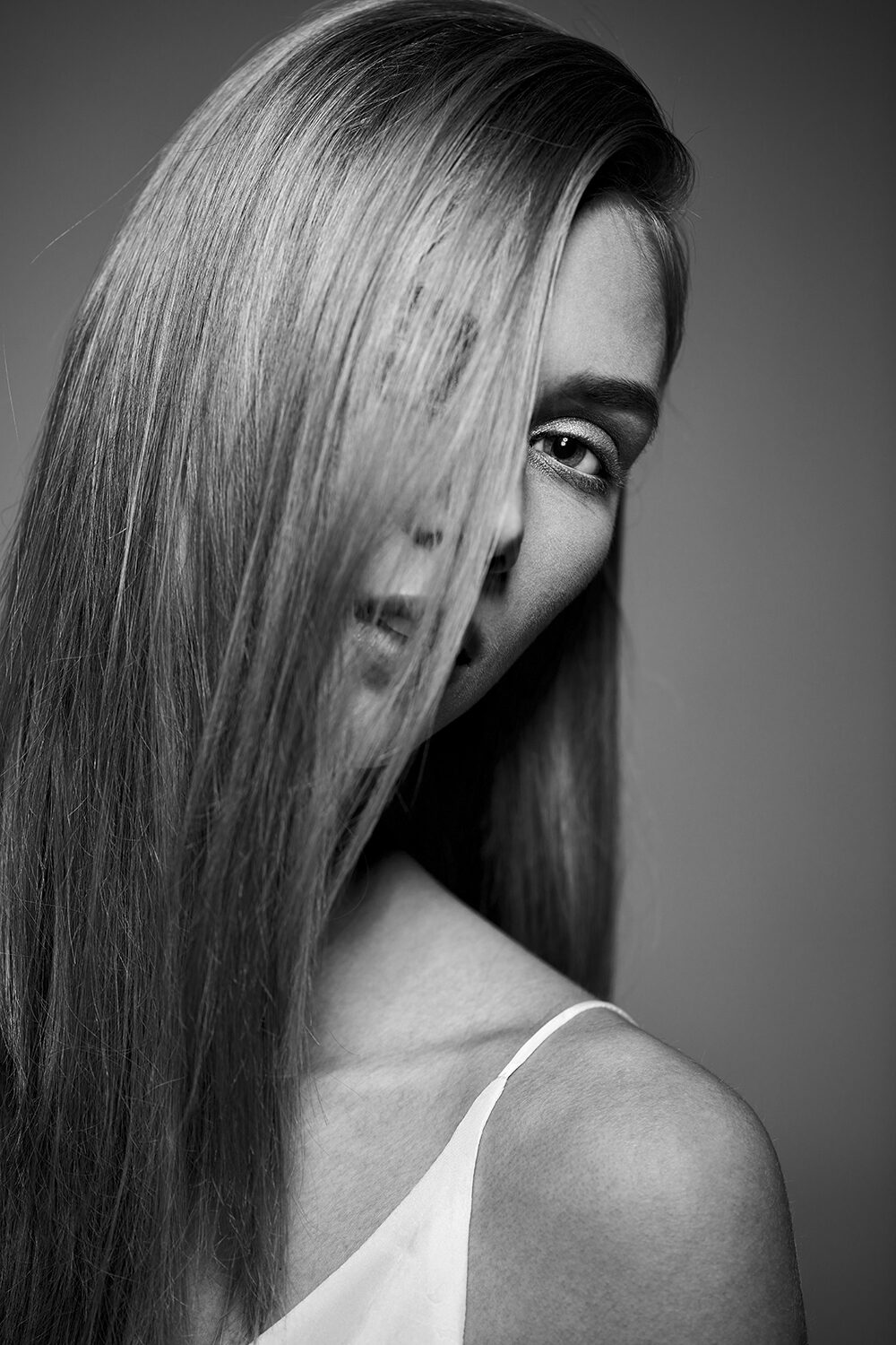 Schwarz-Weiß-Beauty-Portrait eines Models mit ins Gesicht fallendem Haar im Studio.