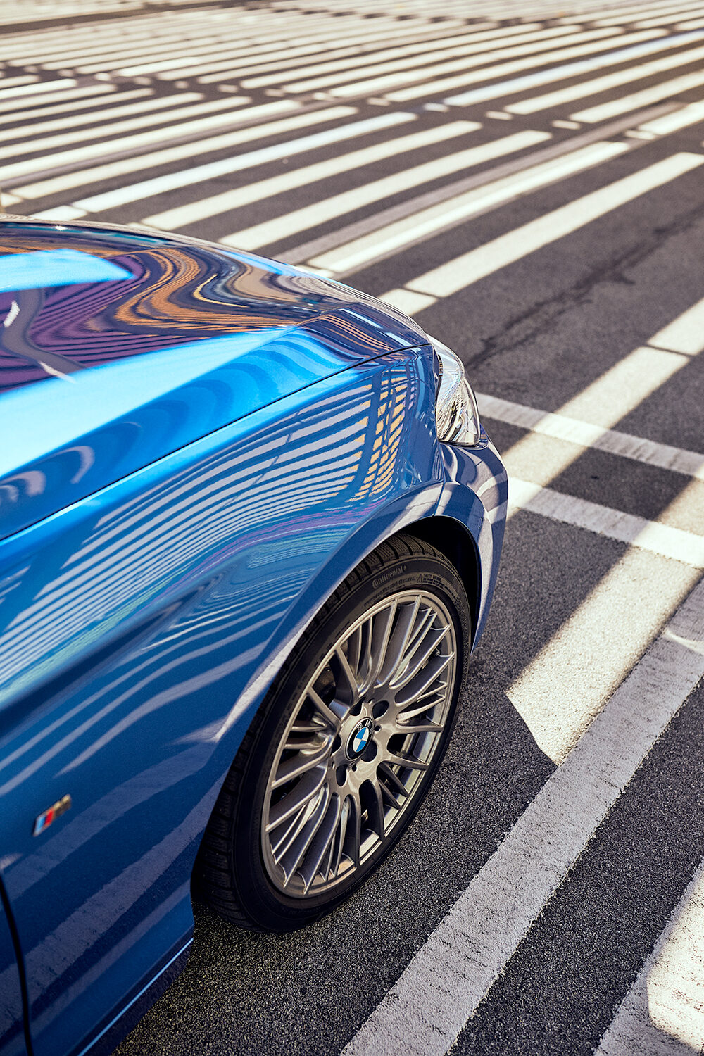 Nahaufnahme der hinteren Flanke und des Leichtmetallrads eines estorilblauen BMW M140i xDrive im Parkhaus des Skyline Plaza in Frankfurt am Main.