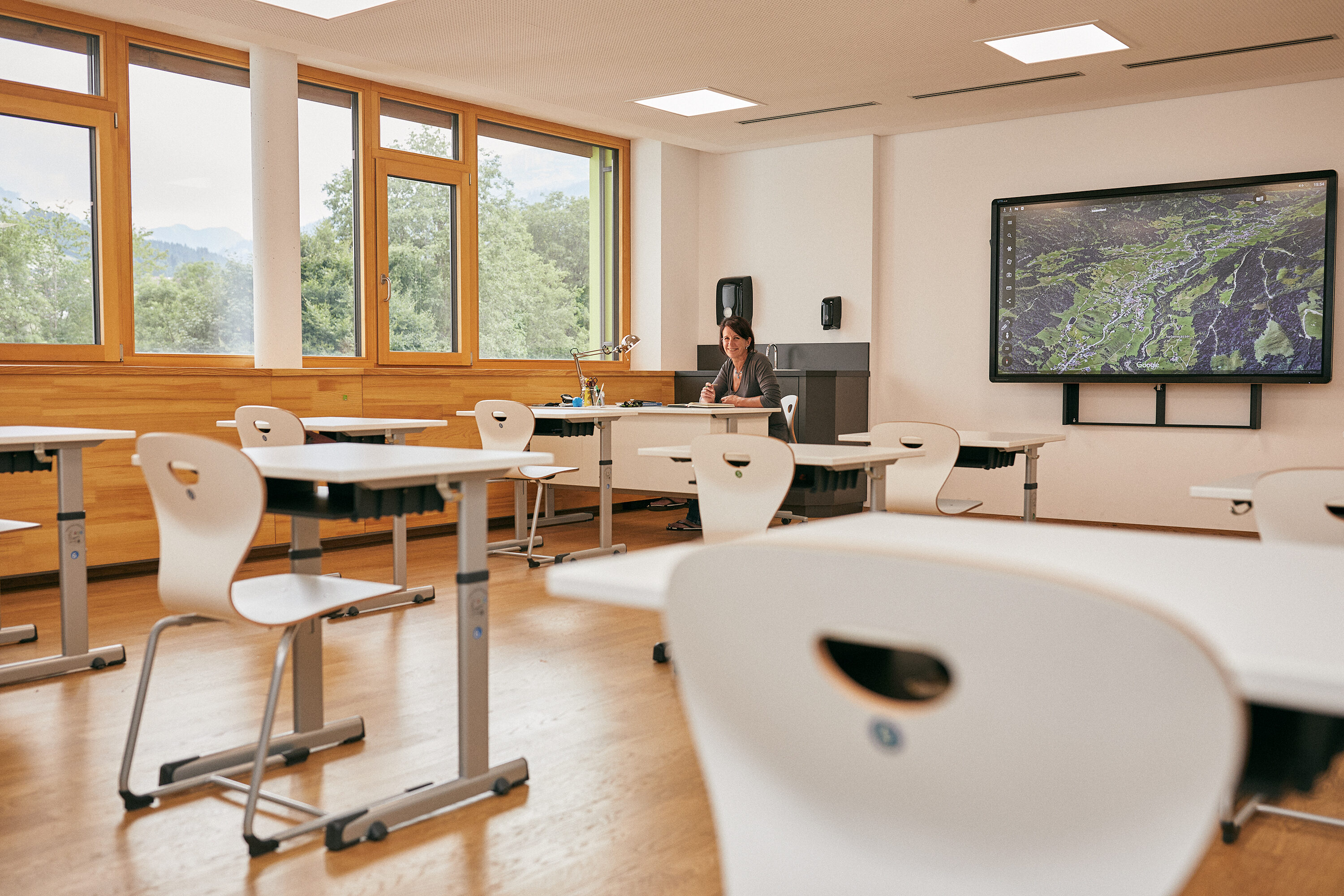 Modernes Klassenzimmer mit Bergblick im Kleinwalsertal, in dem Eliane Fritz an einem Pult arbeitet.