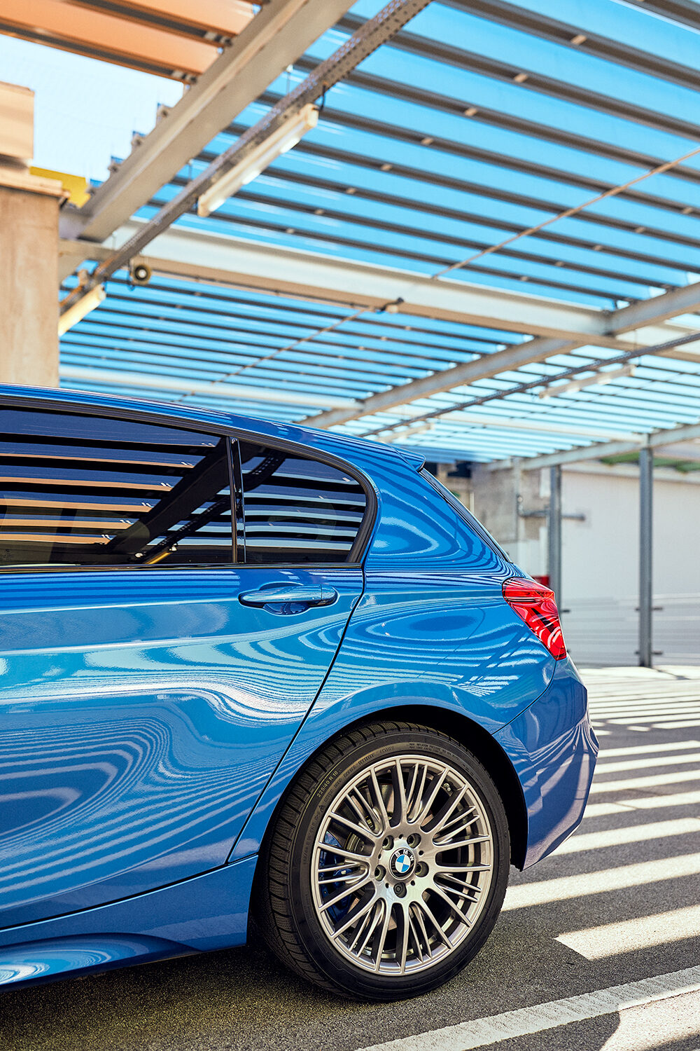 Hintere Seitenansicht eines estorilblauen BMW M140i xDrive mit C-Säule und Leichtmetallrad im Parkhaus des Skyline Plaza in Frankfurt am Main.